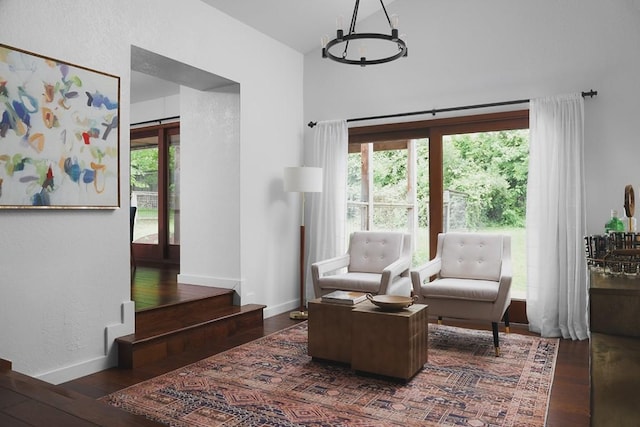 living area with a wealth of natural light, a notable chandelier, baseboards, and hardwood / wood-style flooring