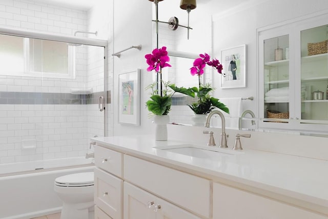 bathroom featuring vanity, toilet, and bath / shower combo with glass door