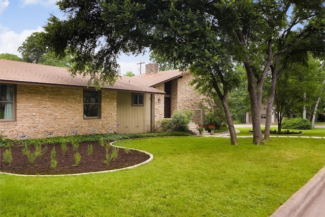 exterior space featuring stone siding, a chimney, and a front yard