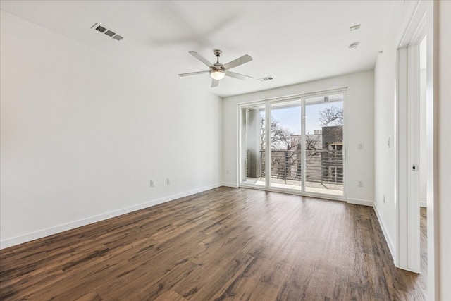 spare room with dark wood-style floors, visible vents, baseboards, and ceiling fan