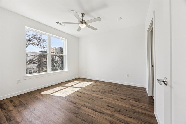 empty room featuring dark wood finished floors, baseboards, visible vents, and a ceiling fan