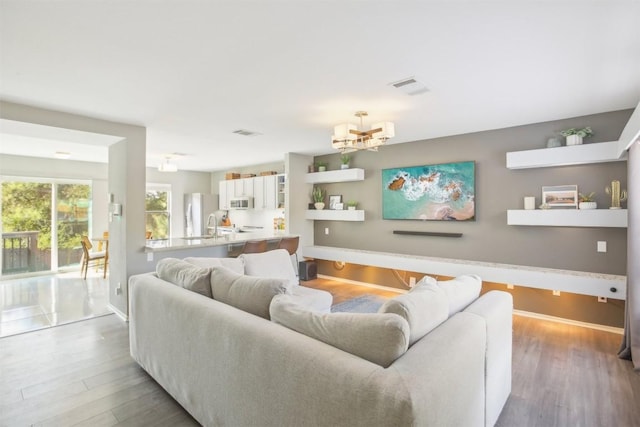 living room with visible vents, baseboards, and wood finished floors