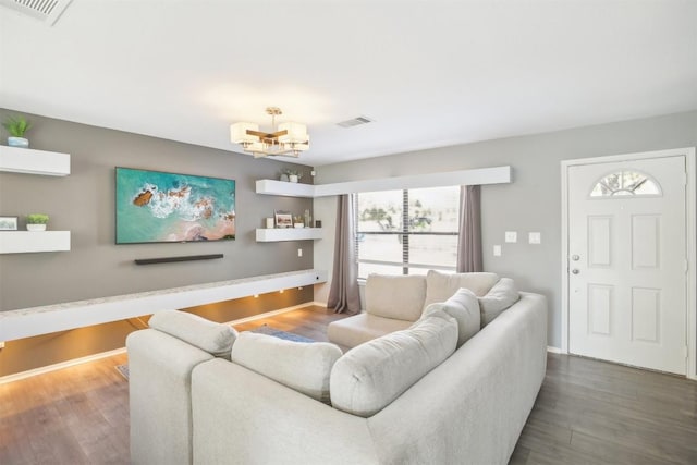 living area featuring an inviting chandelier, dark wood-style floors, and visible vents