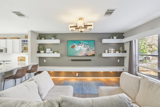 living area featuring wood finished floors, visible vents, and a chandelier