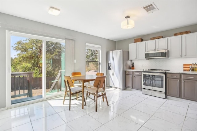 kitchen with visible vents, marble finish floor, light stone counters, backsplash, and appliances with stainless steel finishes