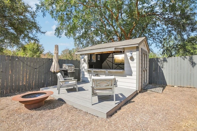 exterior space featuring an outbuilding, area for grilling, outdoor dry bar, a fenced backyard, and a fire pit