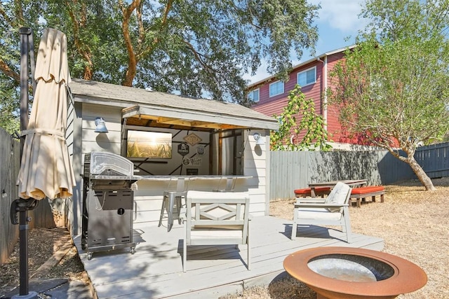 view of patio with a wooden deck, a grill, outdoor dry bar, and fence