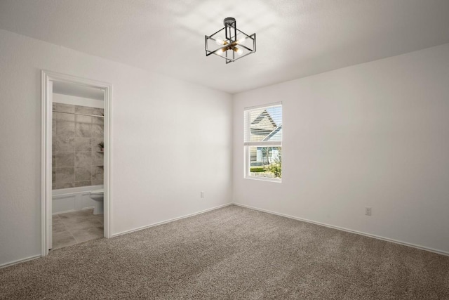 unfurnished bedroom featuring carpet floors, baseboards, an inviting chandelier, and connected bathroom