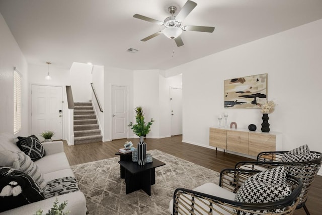 living area featuring visible vents, wood finished floors, baseboards, ceiling fan, and stairway