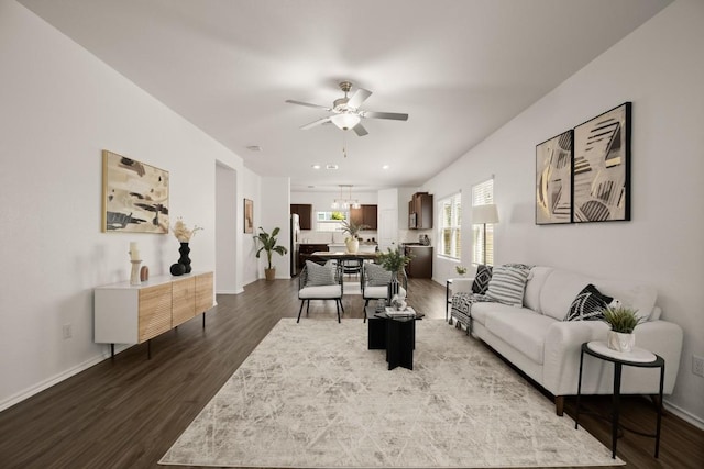 living area with baseboards, dark wood-style flooring, and ceiling fan