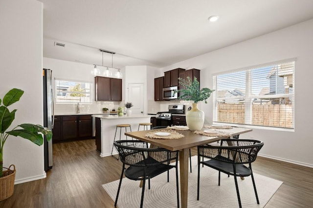 dining room featuring baseboards, plenty of natural light, wood finished floors, and visible vents