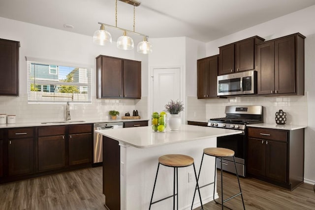 kitchen with a sink, light countertops, stainless steel appliances, and dark wood-style flooring