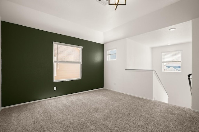carpeted empty room featuring baseboards, a wealth of natural light, and visible vents