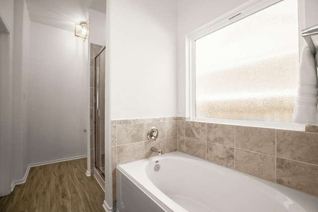 full bathroom with wood finished floors, a stall shower, and a bath