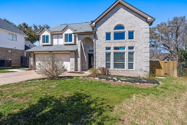 traditional home with brick siding, a front lawn, fence, driveway, and an attached garage