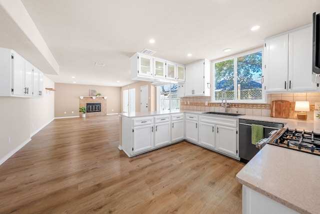 kitchen with tasteful backsplash, dishwasher, a tile fireplace, a peninsula, and a sink