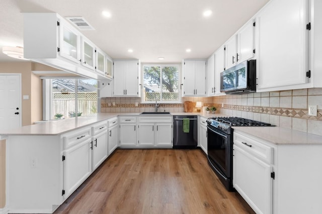 kitchen with visible vents, stainless steel microwave, black gas range oven, a peninsula, and dishwasher