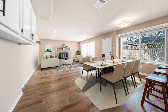 dining room featuring visible vents, a glass covered fireplace, recessed lighting, light wood-style floors, and baseboards