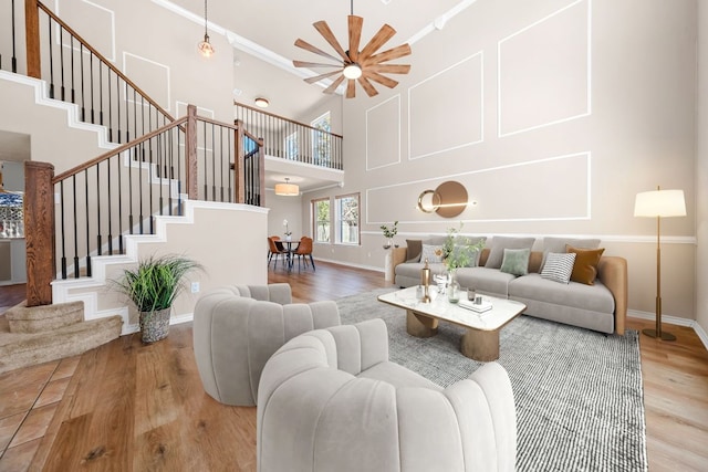 living area with stairway, baseboards, a high ceiling, and wood finished floors