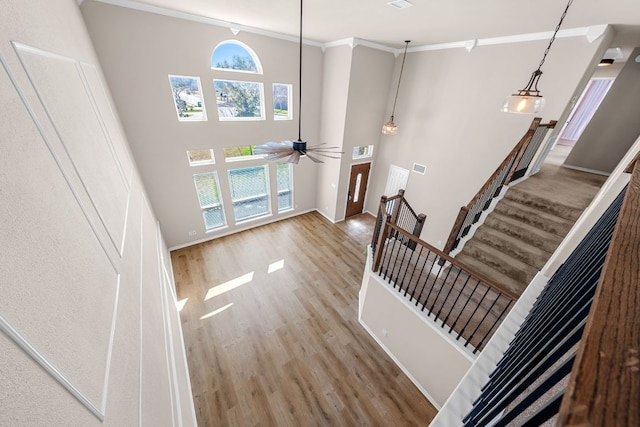 entrance foyer with wood finished floors, baseboards, a high ceiling, ceiling fan, and ornamental molding