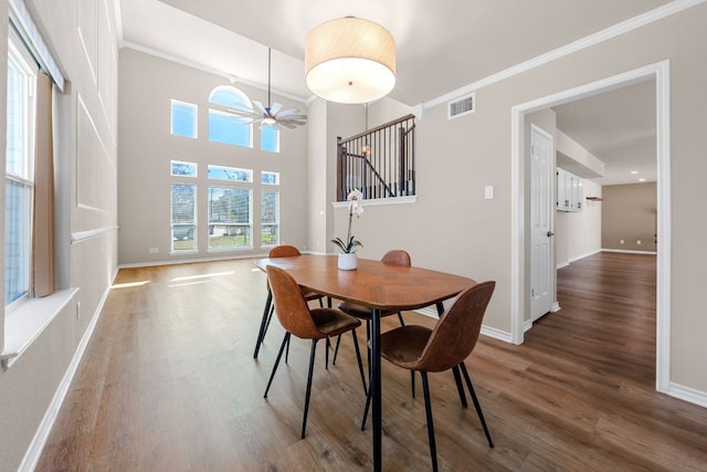 dining space featuring wood finished floors, stairway, baseboards, and visible vents