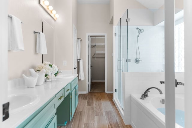 bathroom with a walk in closet, a garden tub, a sink, a shower stall, and double vanity