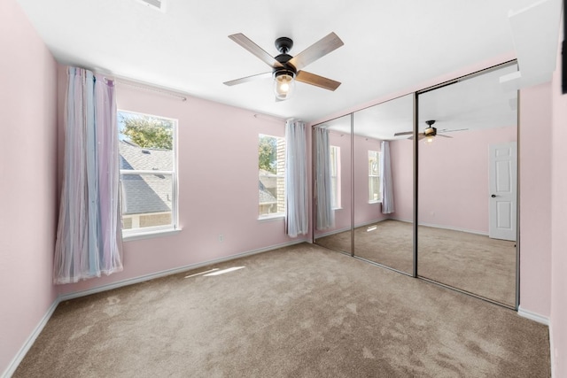 unfurnished bedroom with multiple windows, a ceiling fan, and carpet flooring