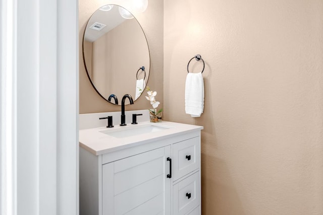 bathroom with vanity, a textured wall, and visible vents