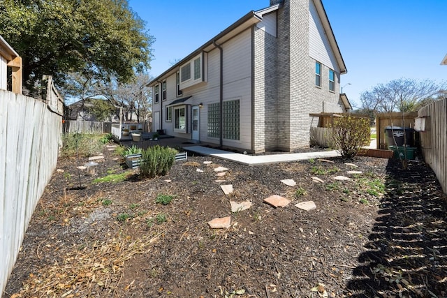 back of house with brick siding, a patio area, a chimney, and a fenced backyard