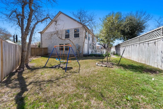 rear view of house featuring a lawn, a fenced backyard, brick siding, and a playground