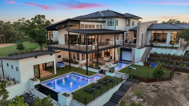 rear view of property with a fenced backyard, stucco siding, a standing seam roof, stairway, and outdoor lounge area
