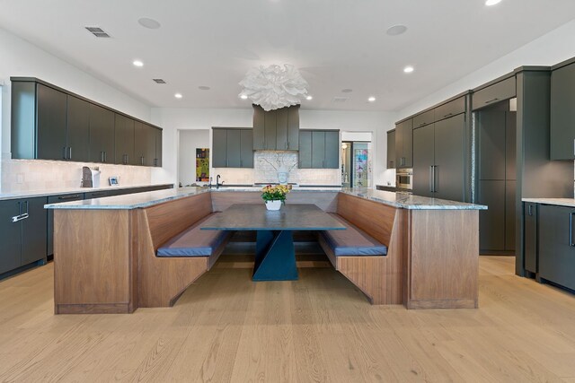 kitchen with stainless steel oven, visible vents, a spacious island, and light wood finished floors