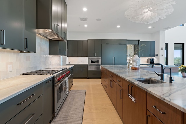 kitchen with light stone counters, recessed lighting, a sink, decorative backsplash, and high quality appliances