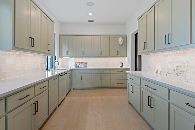 kitchen featuring tasteful backsplash, a sink, light countertops, light wood-style flooring, and stainless steel dishwasher