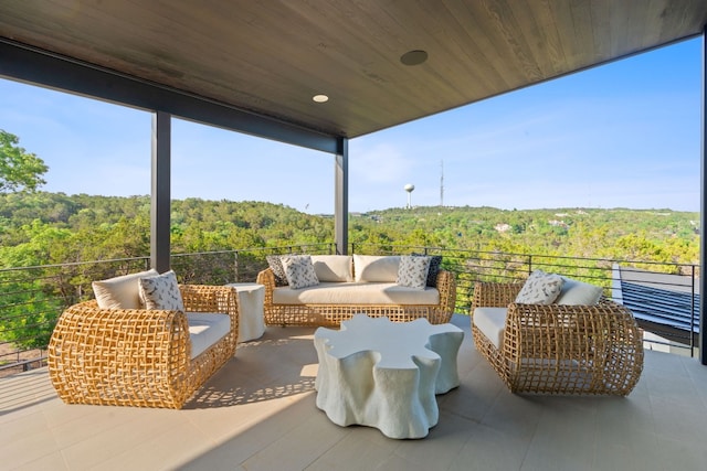view of patio featuring a wooded view and a balcony