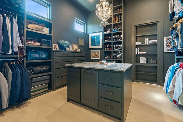 walk in closet with a notable chandelier and light wood-type flooring