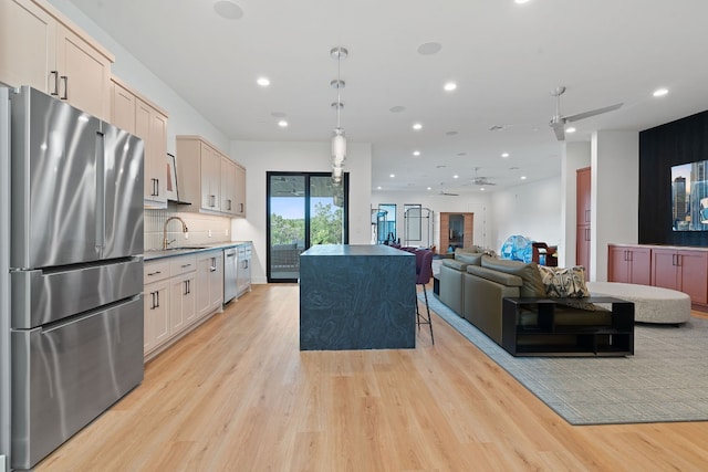 kitchen with a sink, backsplash, appliances with stainless steel finishes, and light wood-style flooring