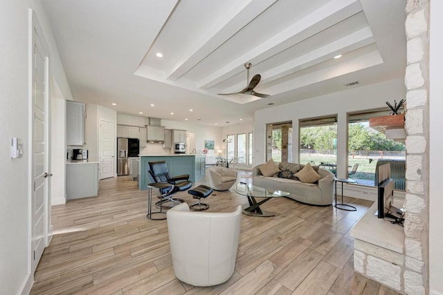 living area with a ceiling fan, visible vents, a healthy amount of sunlight, and light wood-style floors