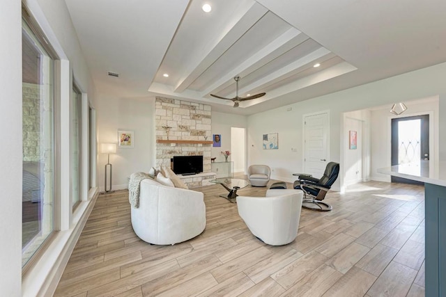living area featuring visible vents, light wood-type flooring, ceiling fan, and a fireplace
