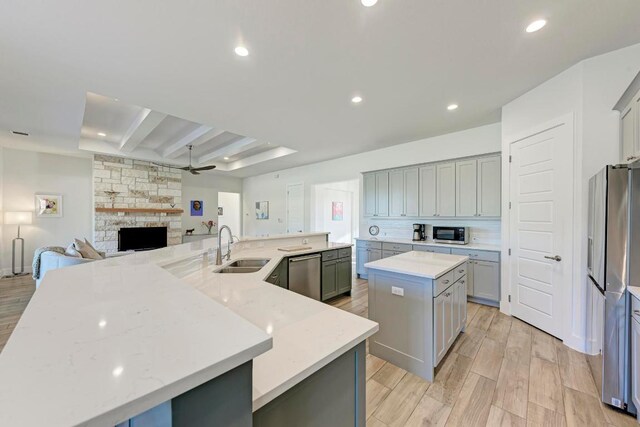 kitchen with a spacious island, appliances with stainless steel finishes, gray cabinets, and a sink