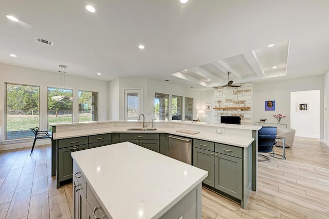 kitchen with stainless steel dishwasher, a spacious island, a fireplace, a sink, and visible vents