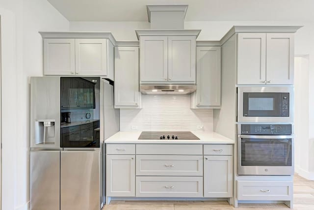 kitchen featuring appliances with stainless steel finishes, light countertops, under cabinet range hood, and backsplash