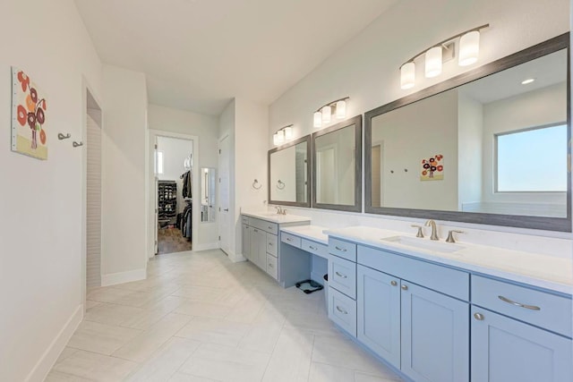 full bathroom with a walk in closet, vanity, and baseboards
