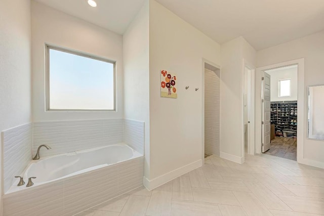 full bath with a garden tub, baseboards, a wealth of natural light, and a spacious closet
