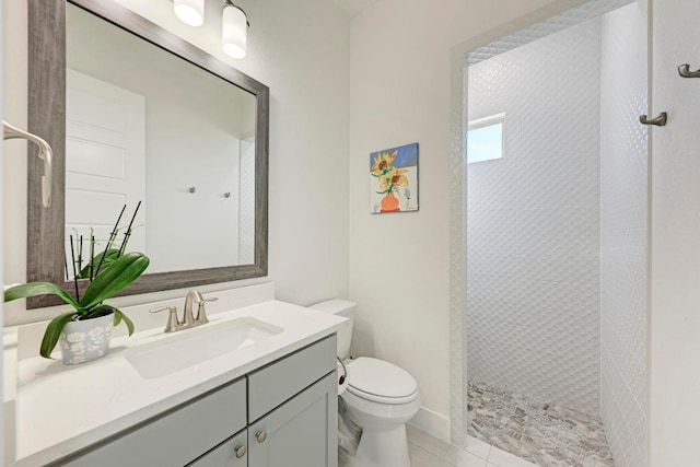 bathroom with a tile shower, toilet, tile patterned flooring, and vanity
