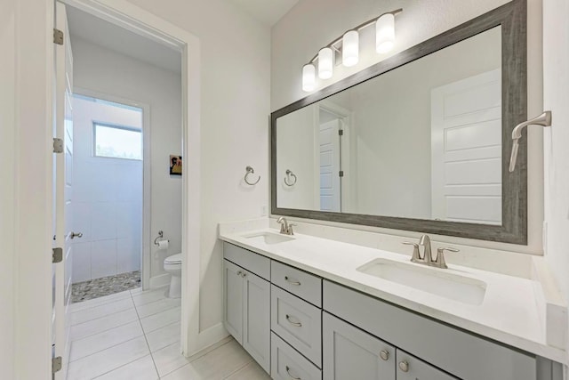 bathroom with double vanity, toilet, tile patterned flooring, and a sink