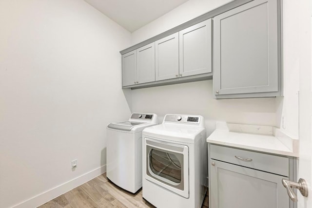 clothes washing area featuring cabinet space, baseboards, independent washer and dryer, and light wood-type flooring