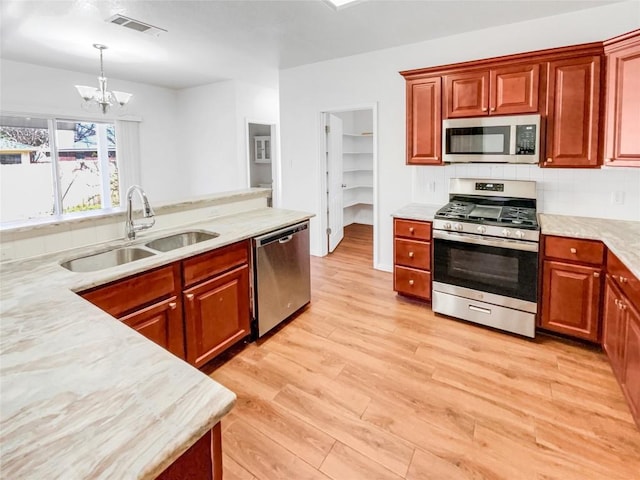 3128 Flinders Reef Ln, Austin, TX 78728 - kitchen with appliances with stainless steel finishes, a chandelier, light wood-type flooring, pendant lighting, and backsplash