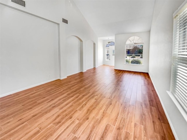 3128 Flinders Reef Ln, Austin, TX 78728 - unfurnished living room featuring light wood-style floors, arched walkways, and high vaulted ceiling