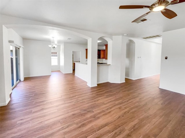 3128 Flinders Reef Ln, Austin, TX 78728 - unfurnished living room featuring wood finished floors, a chandelier, ceiling fan, and arched walkways